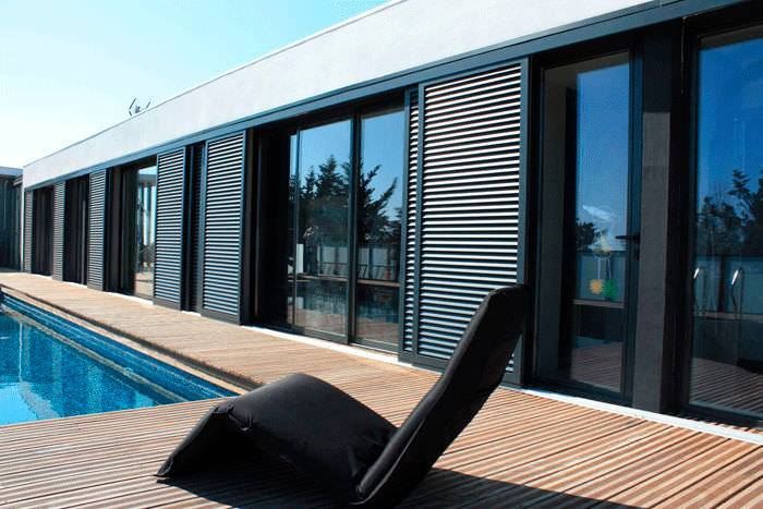 A Chair Is Sitting On A Wooden Deck Next To A Swimming Pool — Huntlee Blinds and Shutters in Badagarang, NSW