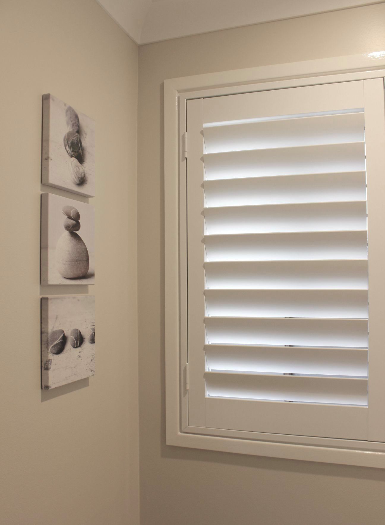 A Close Up Of A White Window With Shutters On It — Huntlee Blinds and Shutters in Badagarang, NSW