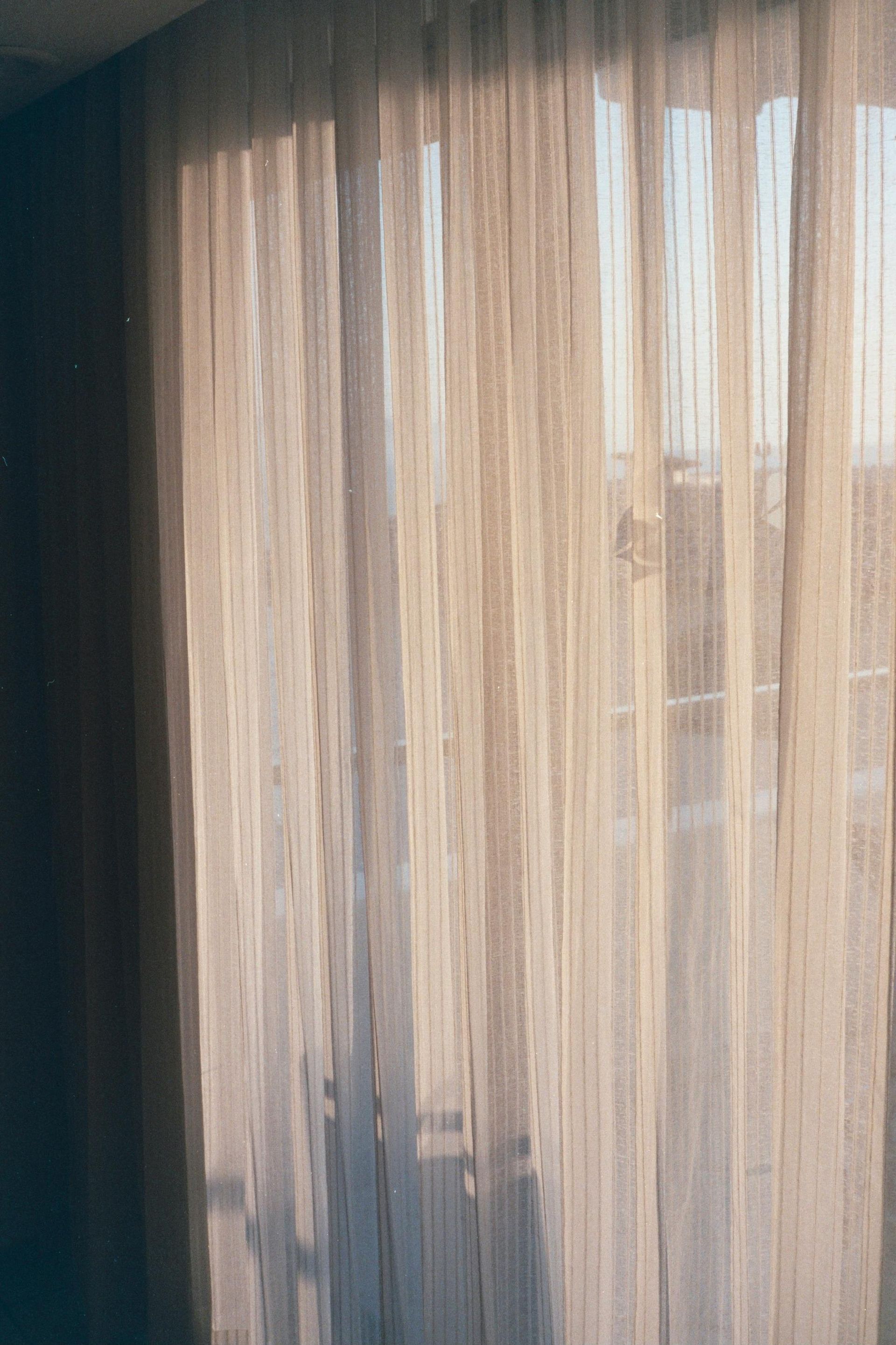 A dining room with a table and chairs and a vase of flowers on the table — Huntlee Blinds and Shutters in Badagarang, NSW