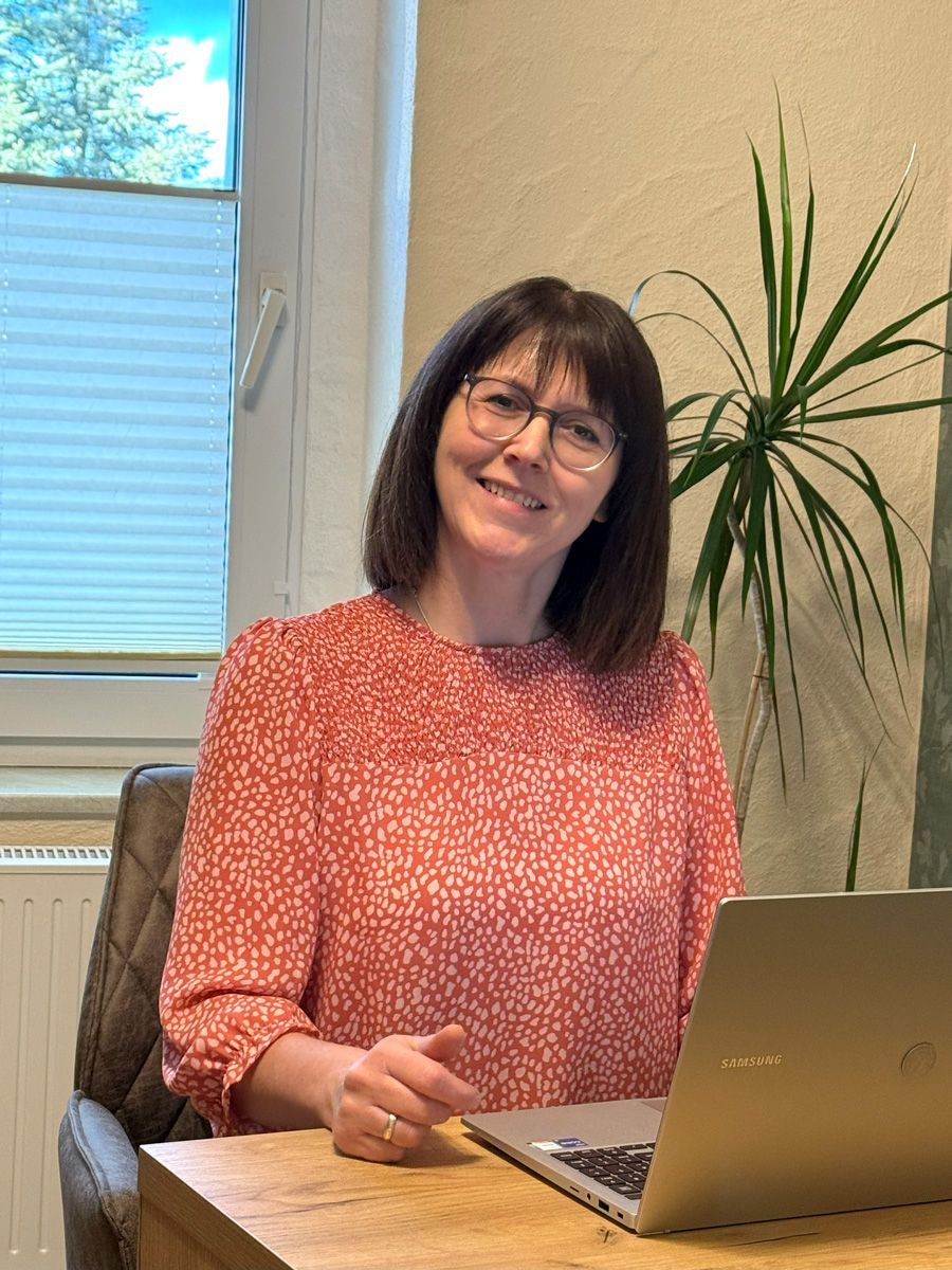 Anja Ebert am Tisch sitzend in ihrer Praxis