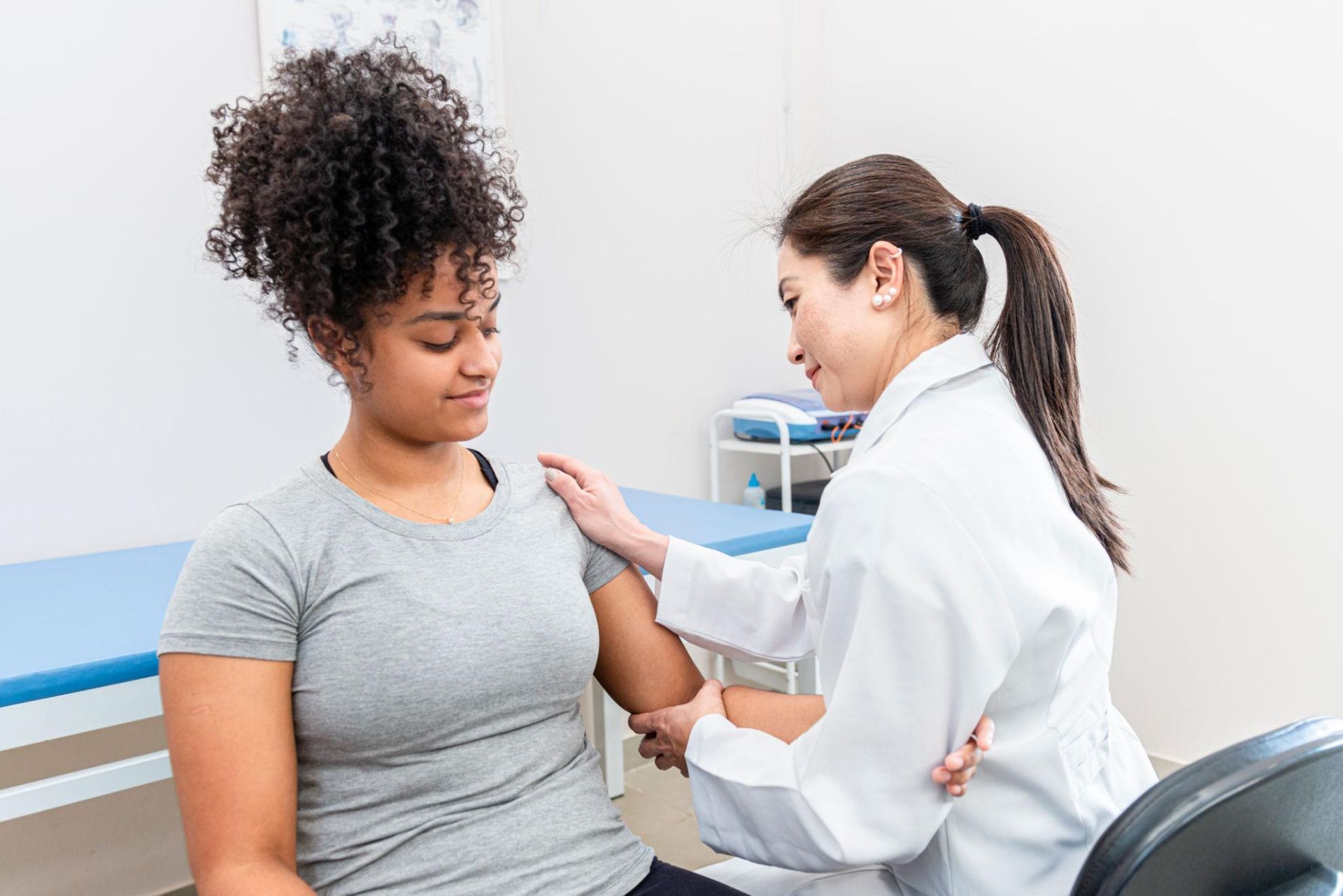 Doctor examining a patient’s arm in a clinic exam room