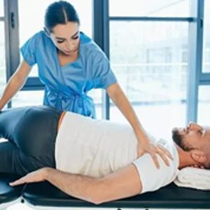 Physical therapist adjusting a patient lying on a table in a bright clinic room
