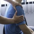 Person resting a hand on another person’s shoulder in a supportive gesture indoors