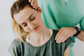 Physical therapist massaging a woman's neck and shoulder as she relaxes