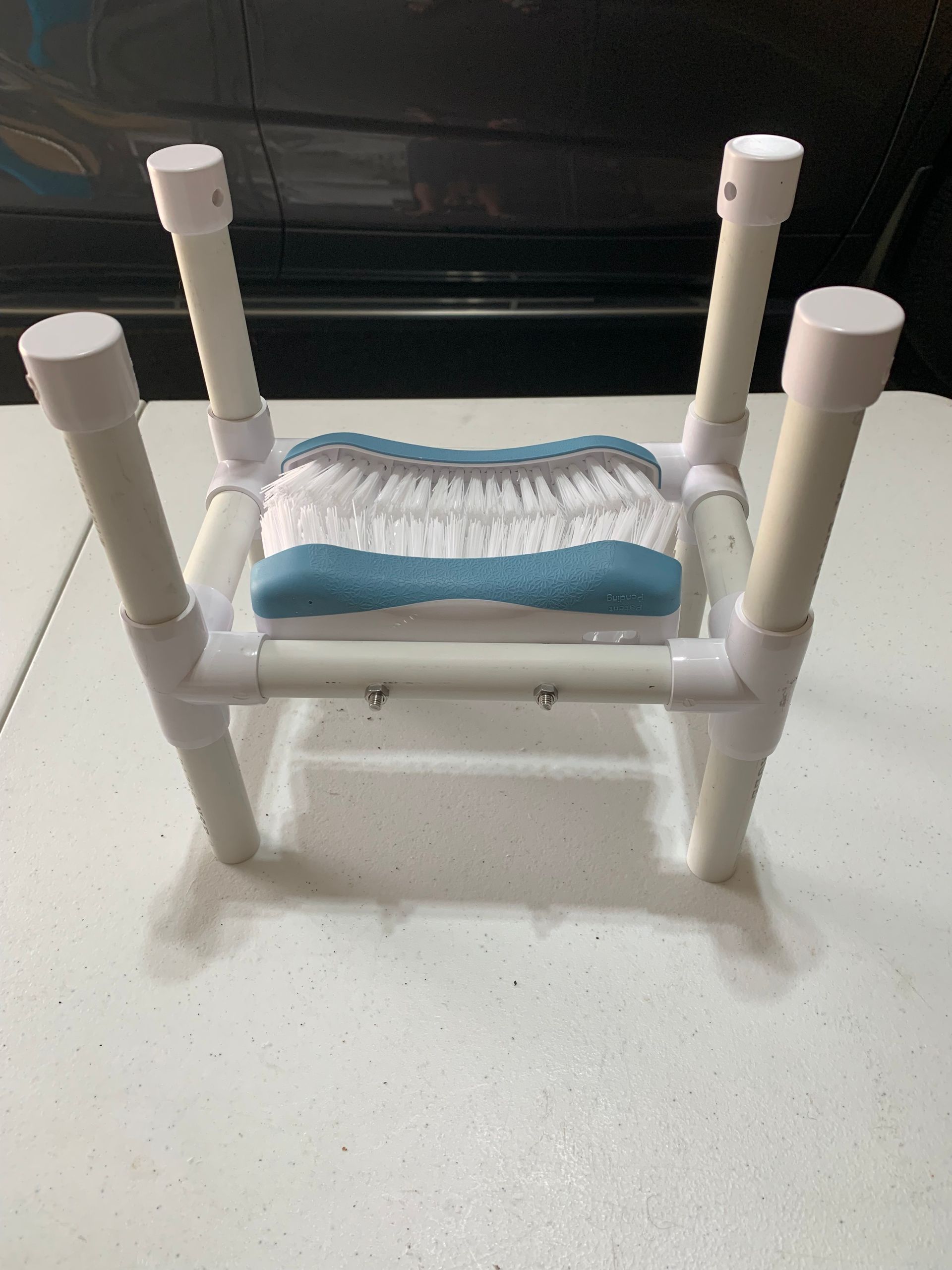 Box with a white PVC pipe assembly and two white scrub brushes. A 