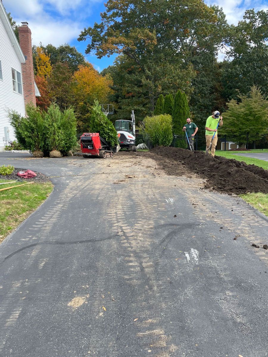 Two Men Working On A Driveway Next To A House — Shrewsbury, MA — Maintenance Free Landscapes