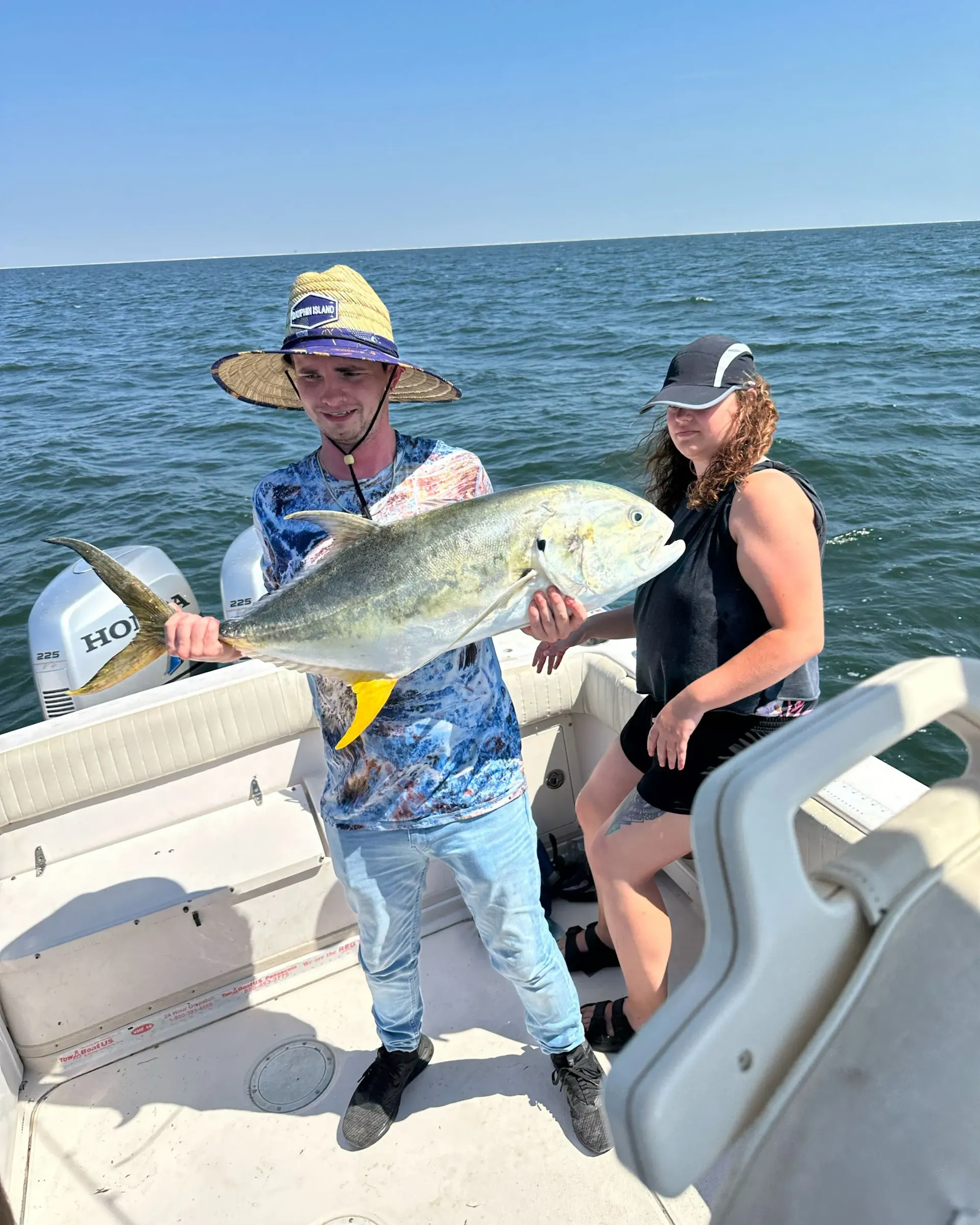 A man and a woman are holding a large fish on a boat.