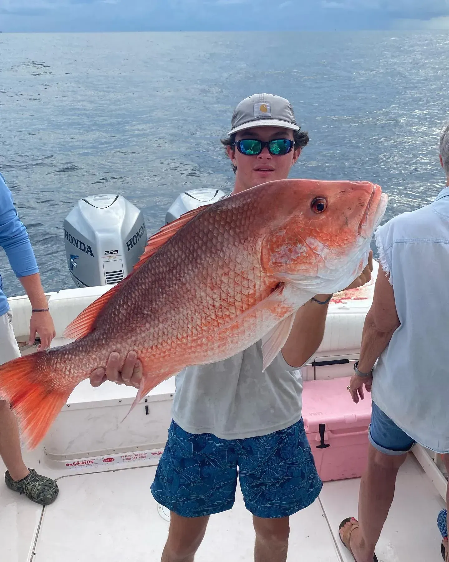 A man is holding a large red fish on a boat.