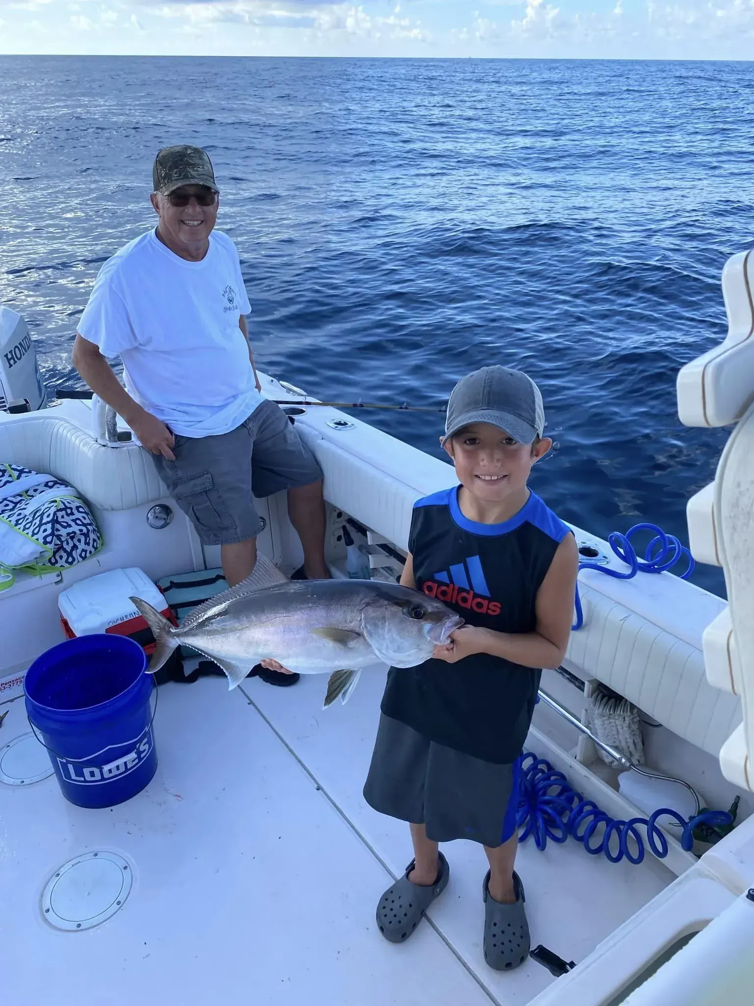 A man and a boy are standing on a boat holding a fish.