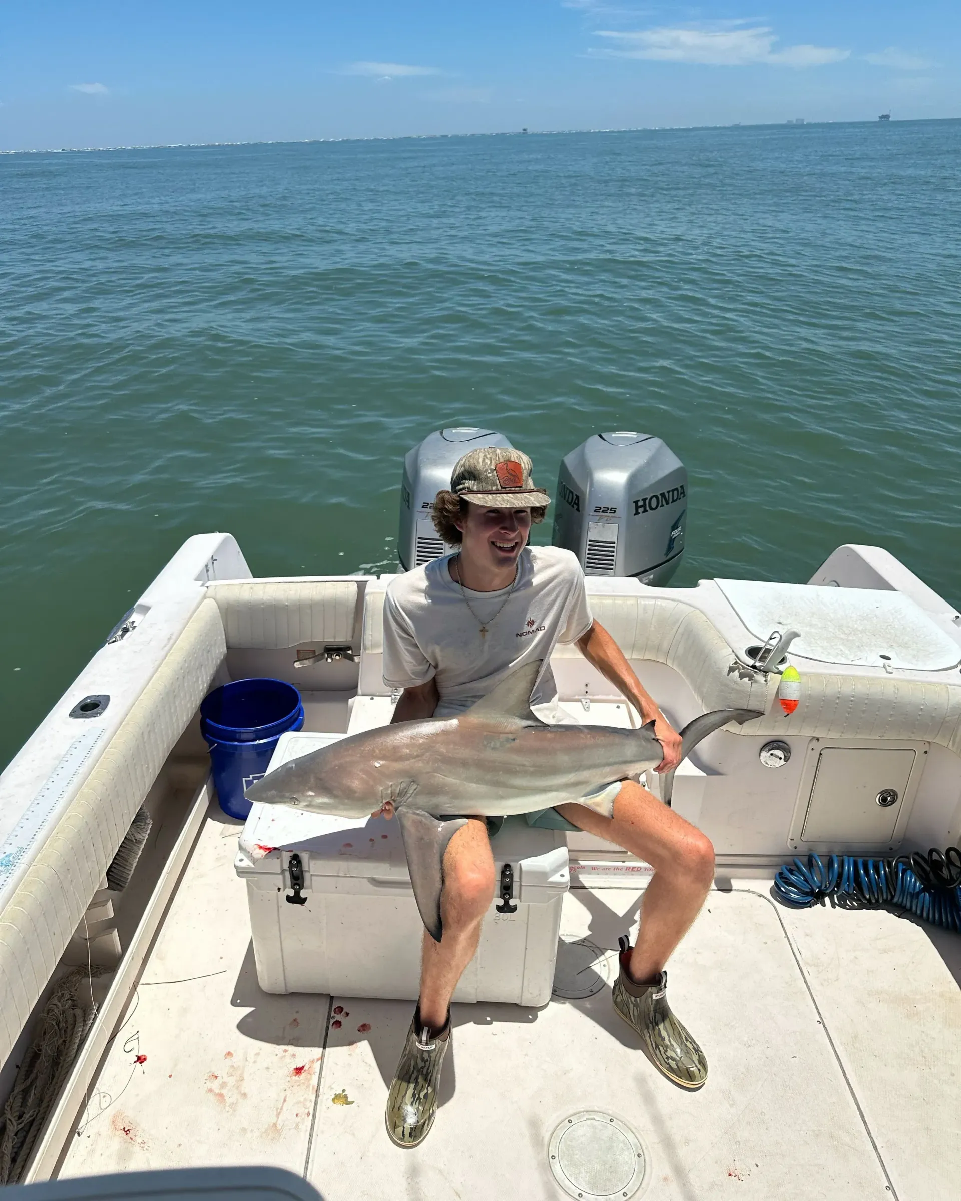 A man is sitting on a boat holding a large fish.