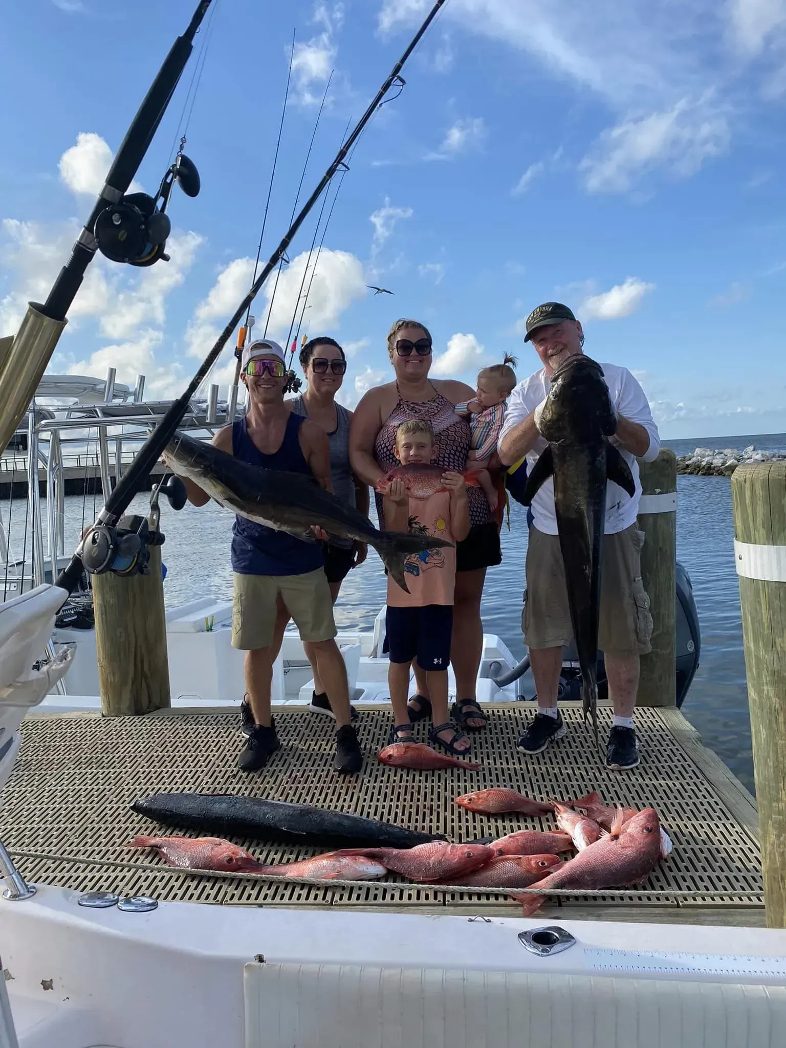 A group of people are standing on a boat holding fish.