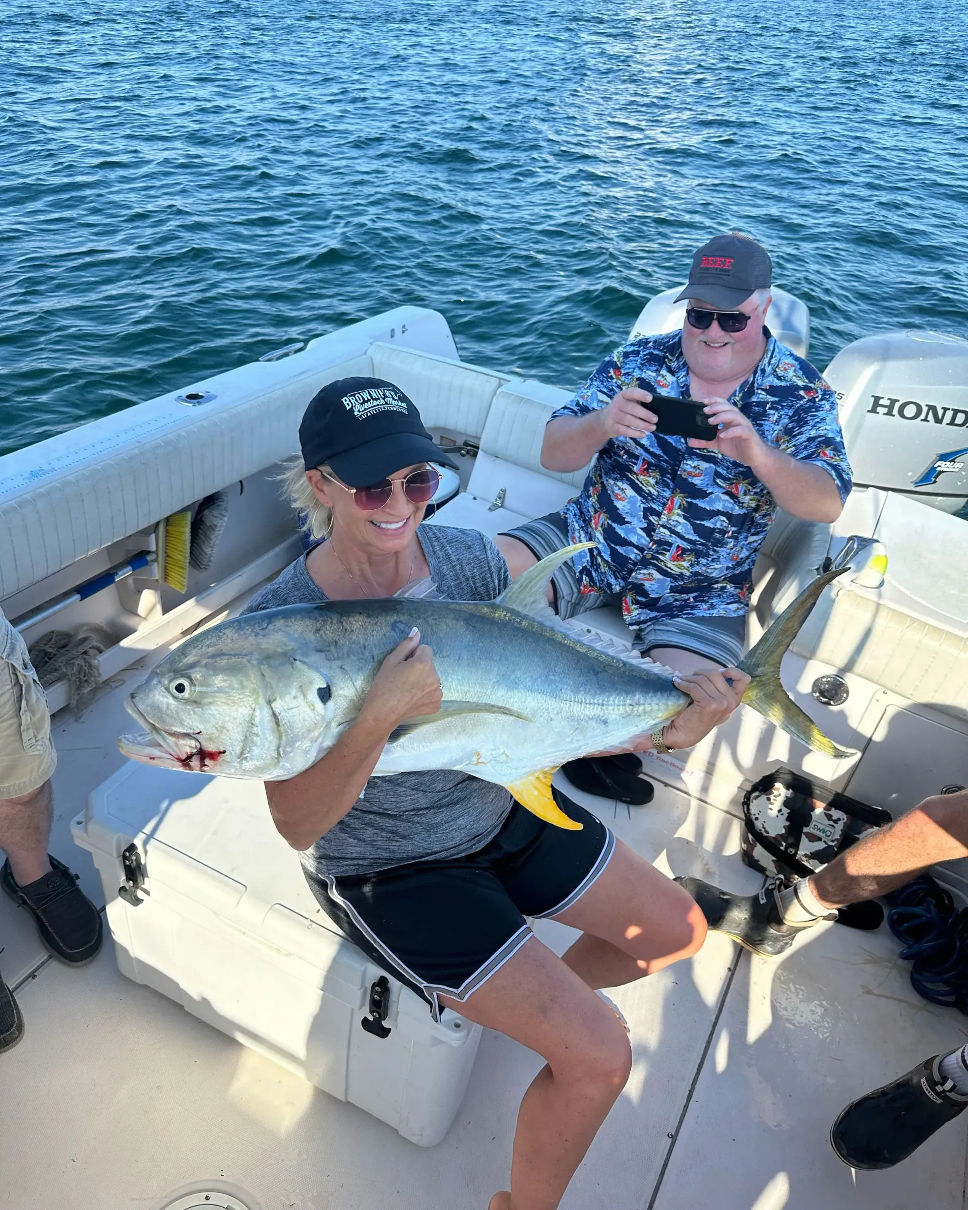 A woman is holding a large fish on a boat.