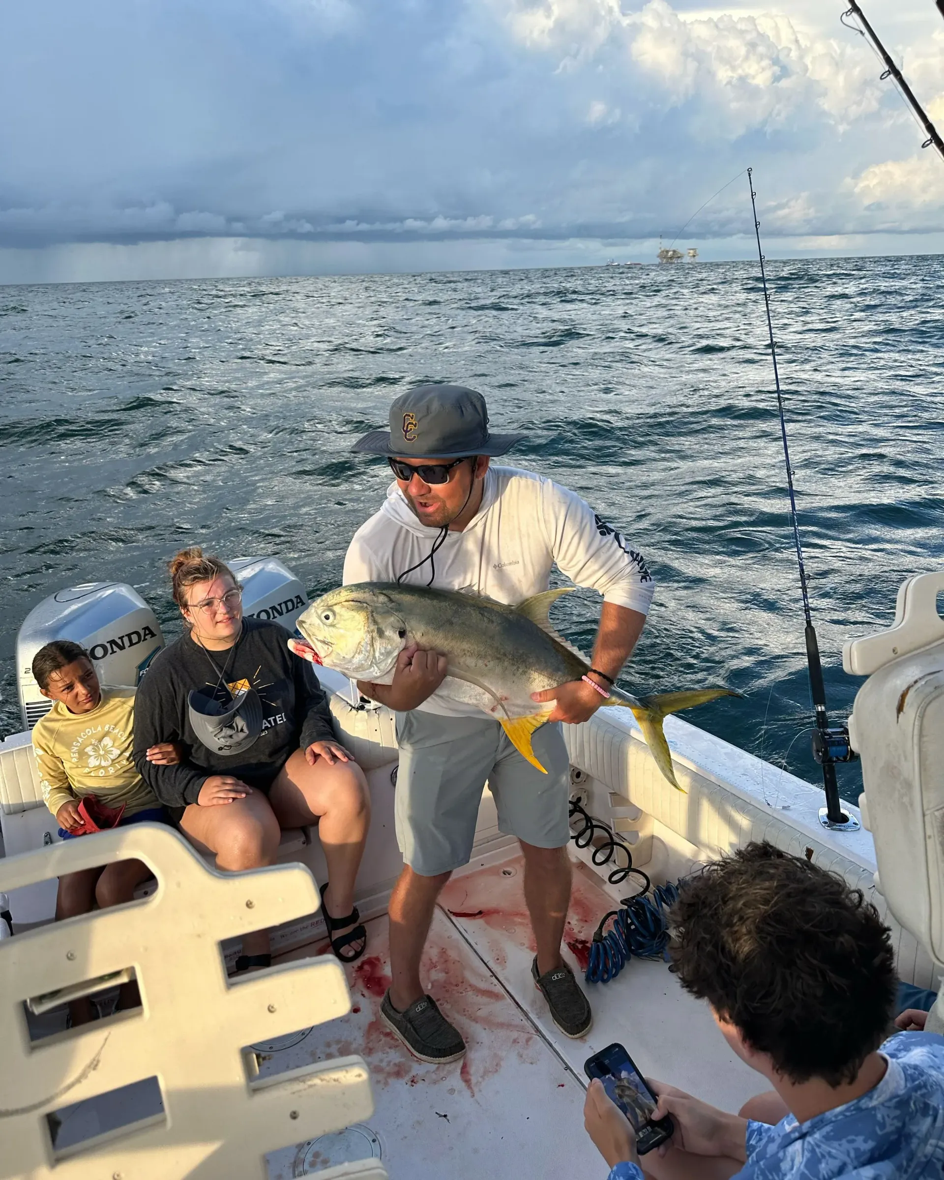 A man is holding a large fish on a boat.