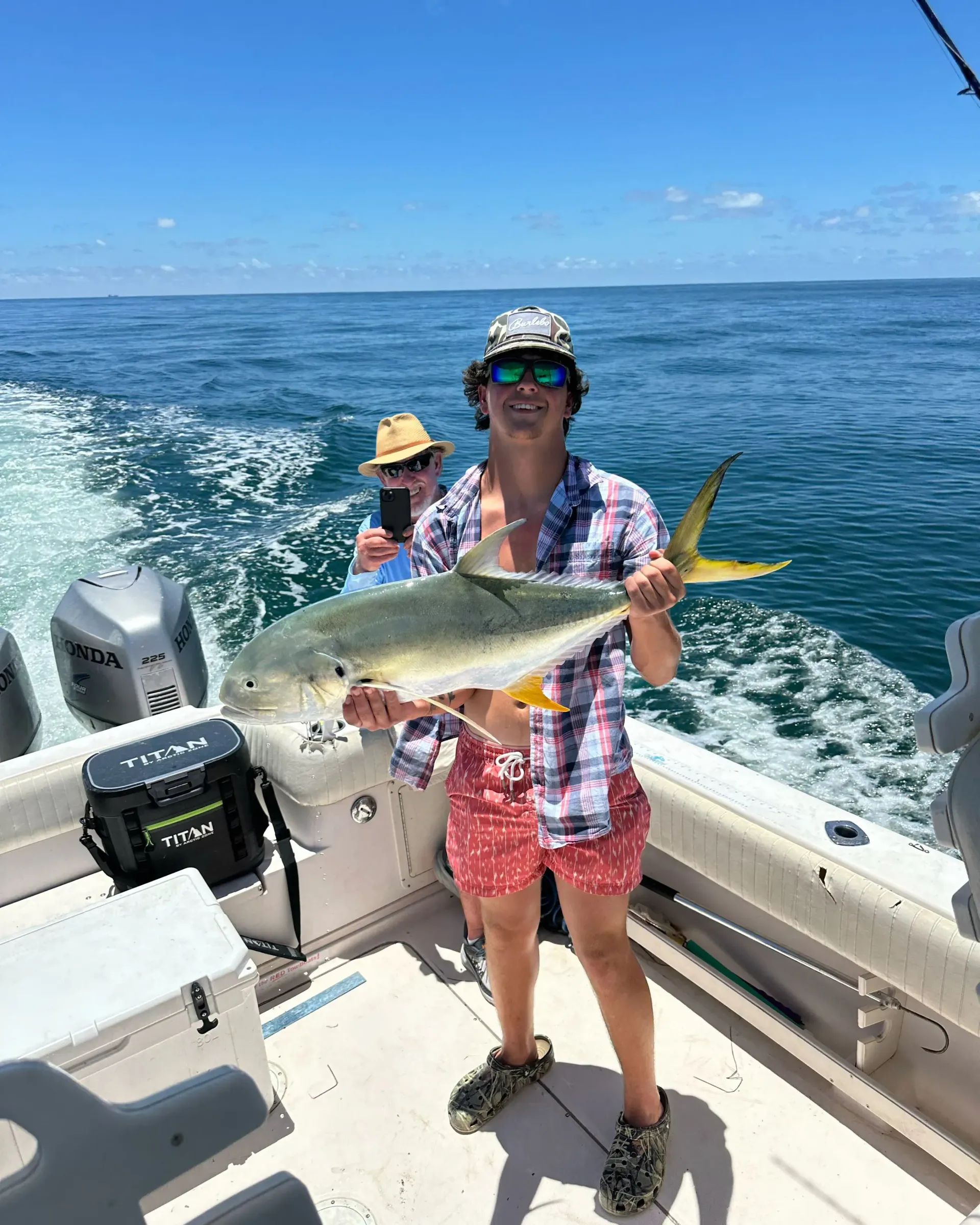 A man is holding a large fish on a boat.