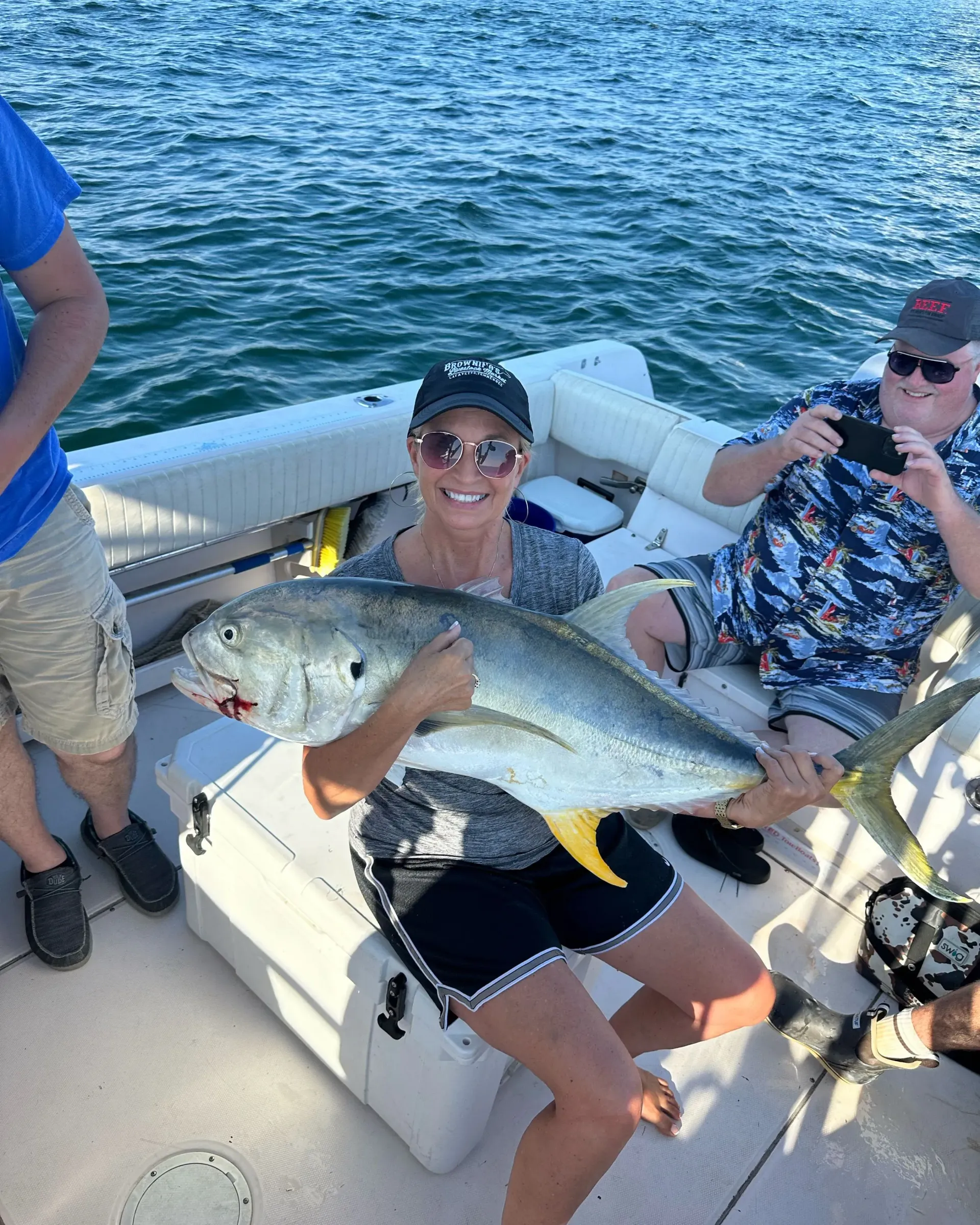 A woman is holding a large fish on a boat.
