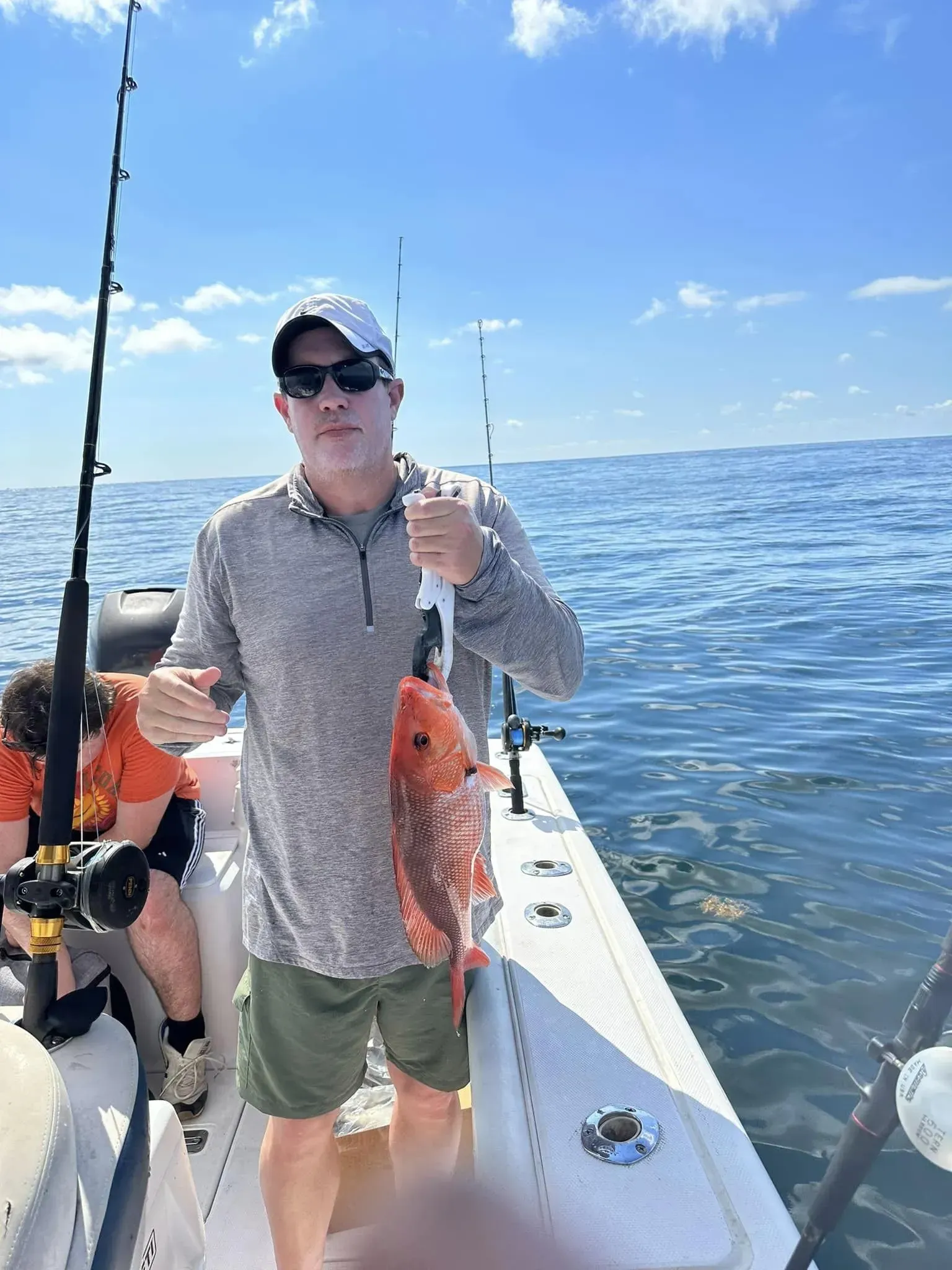A man is standing on a boat holding a fish.