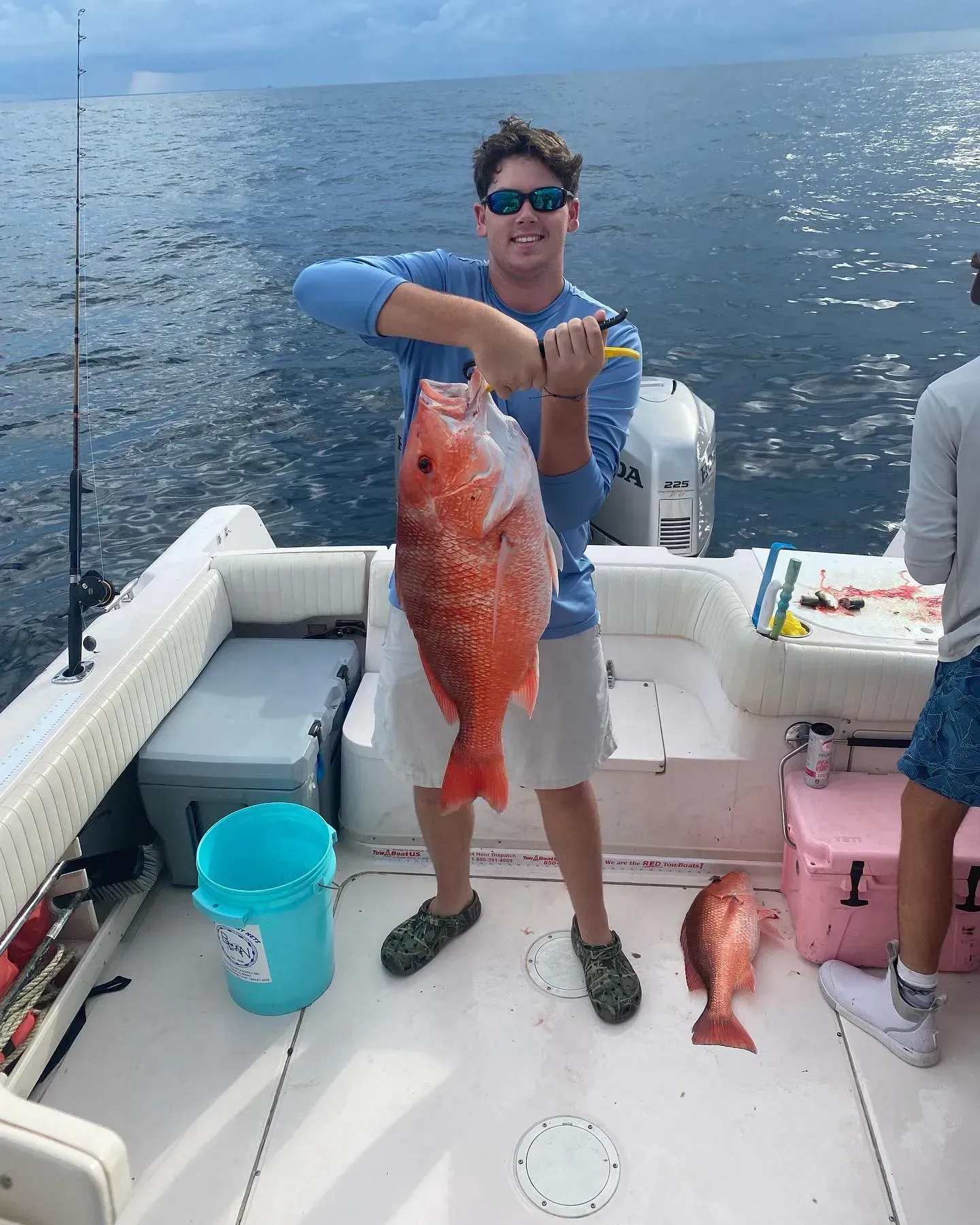 A man is holding a large red fish on a boat.