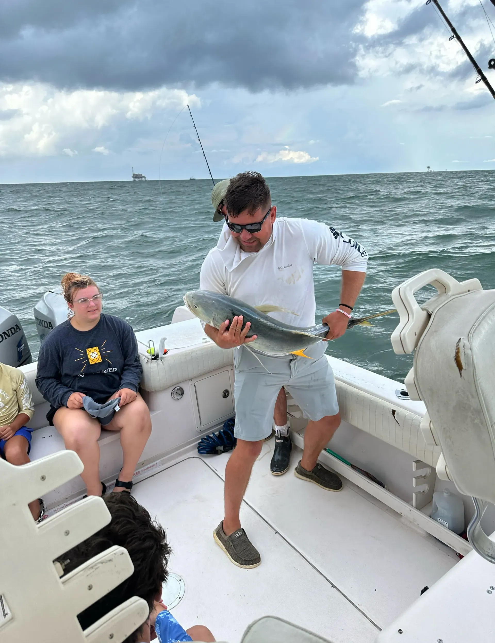 A man is holding a fish on the deck of a boat.