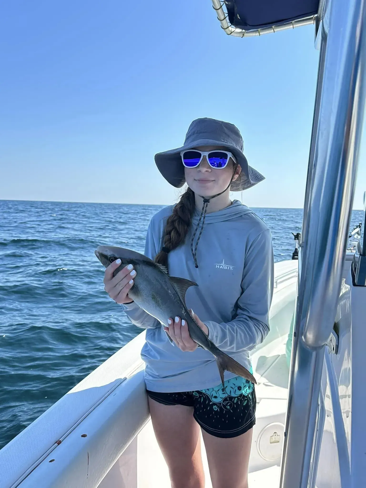 A woman is holding a fish on a boat in the ocean.