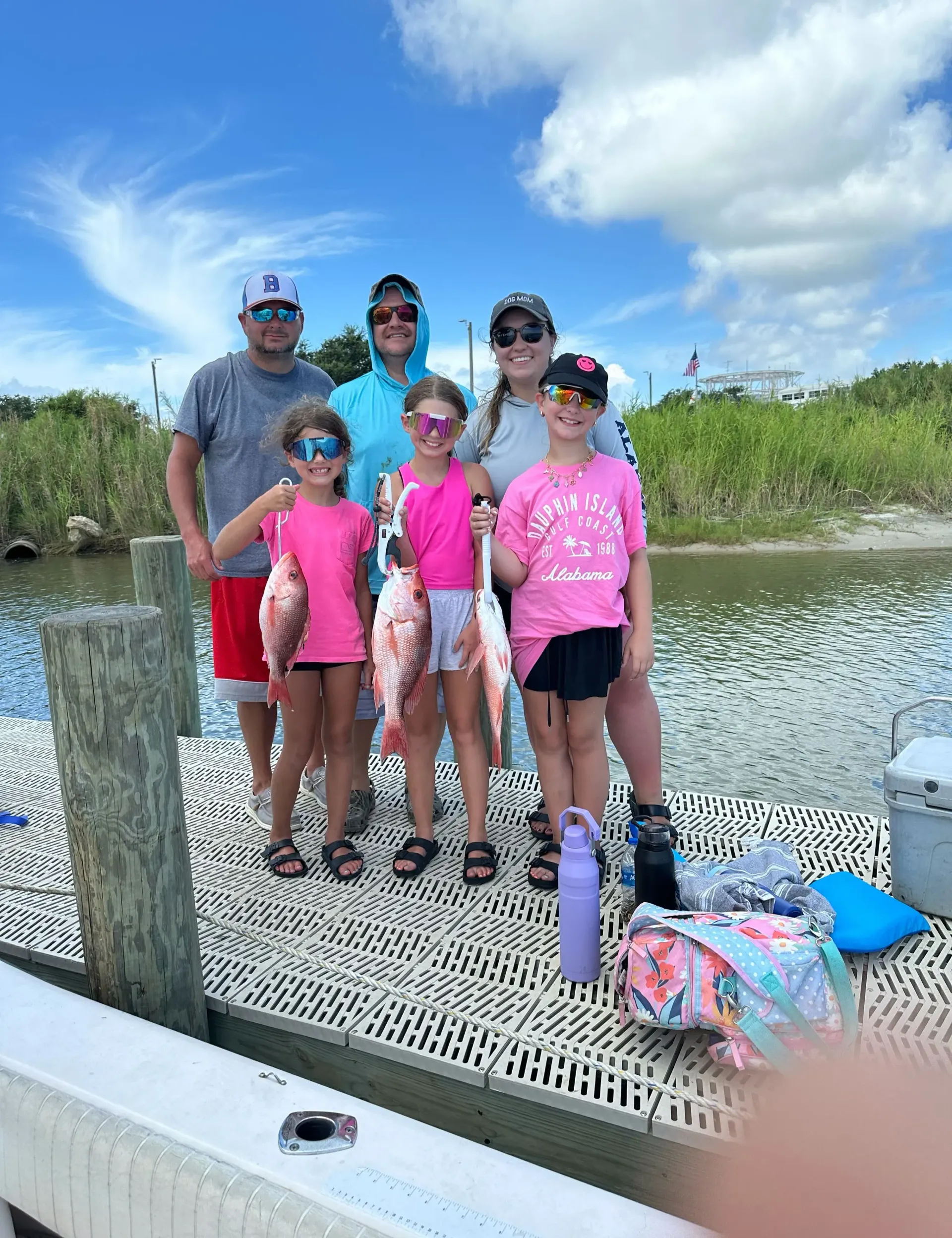 A family is standing on a dock holding fish.