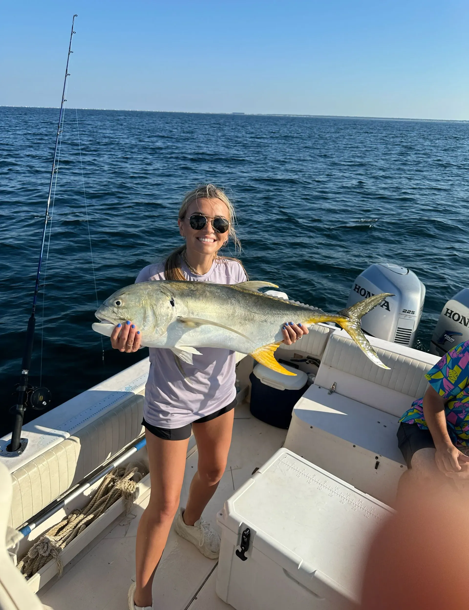 A woman is holding a large fish on a boat.
