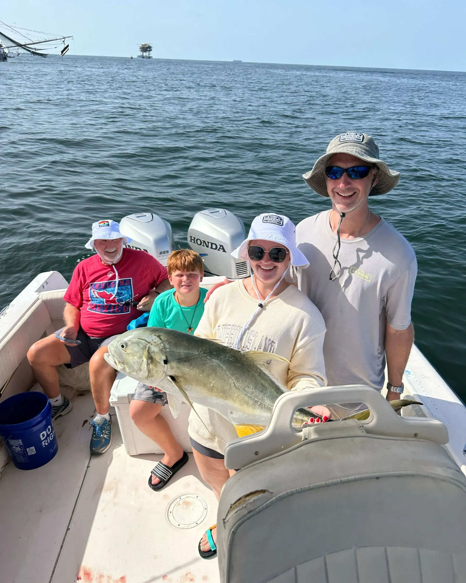 A group of people are sitting on a boat holding a fish.