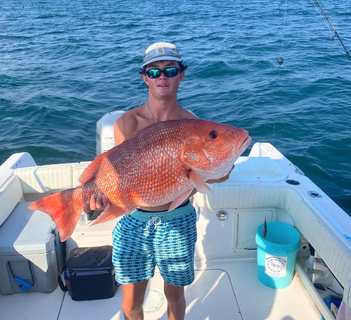 A man is holding a large red fish on a boat.