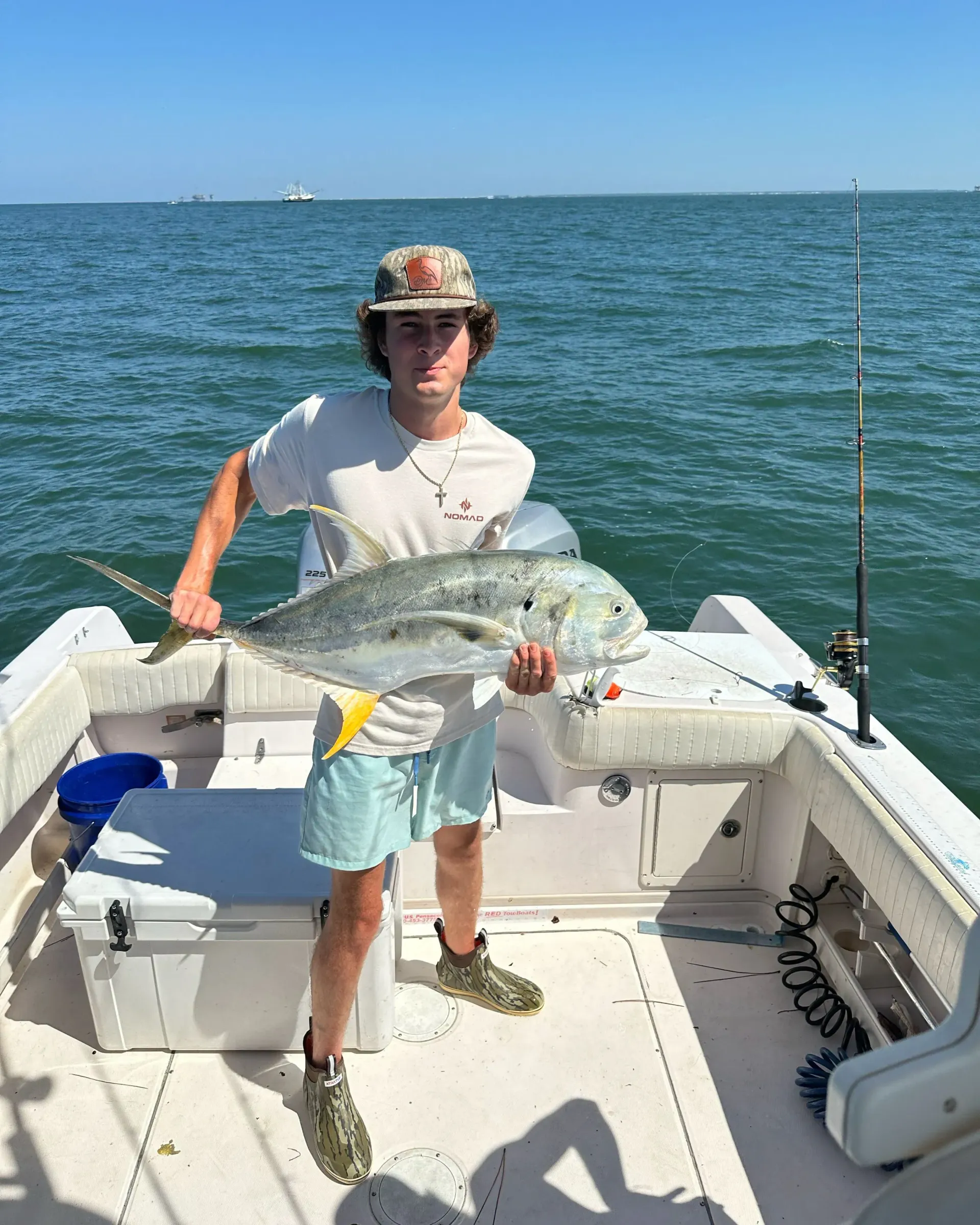 A man is standing on a boat holding a large fish.