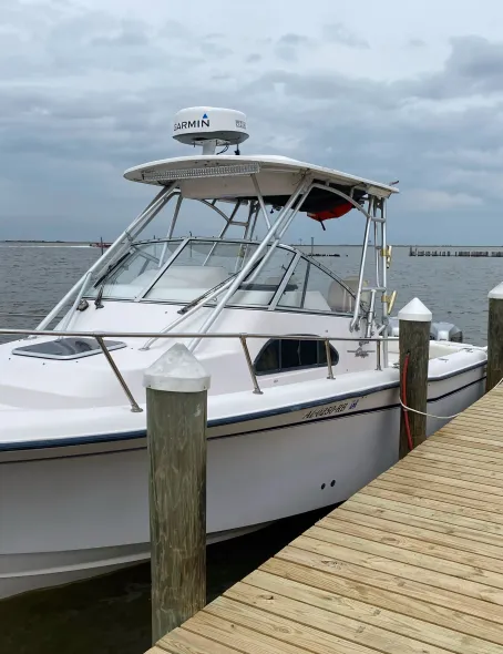 A white boat with a radar on top is docked at a dock