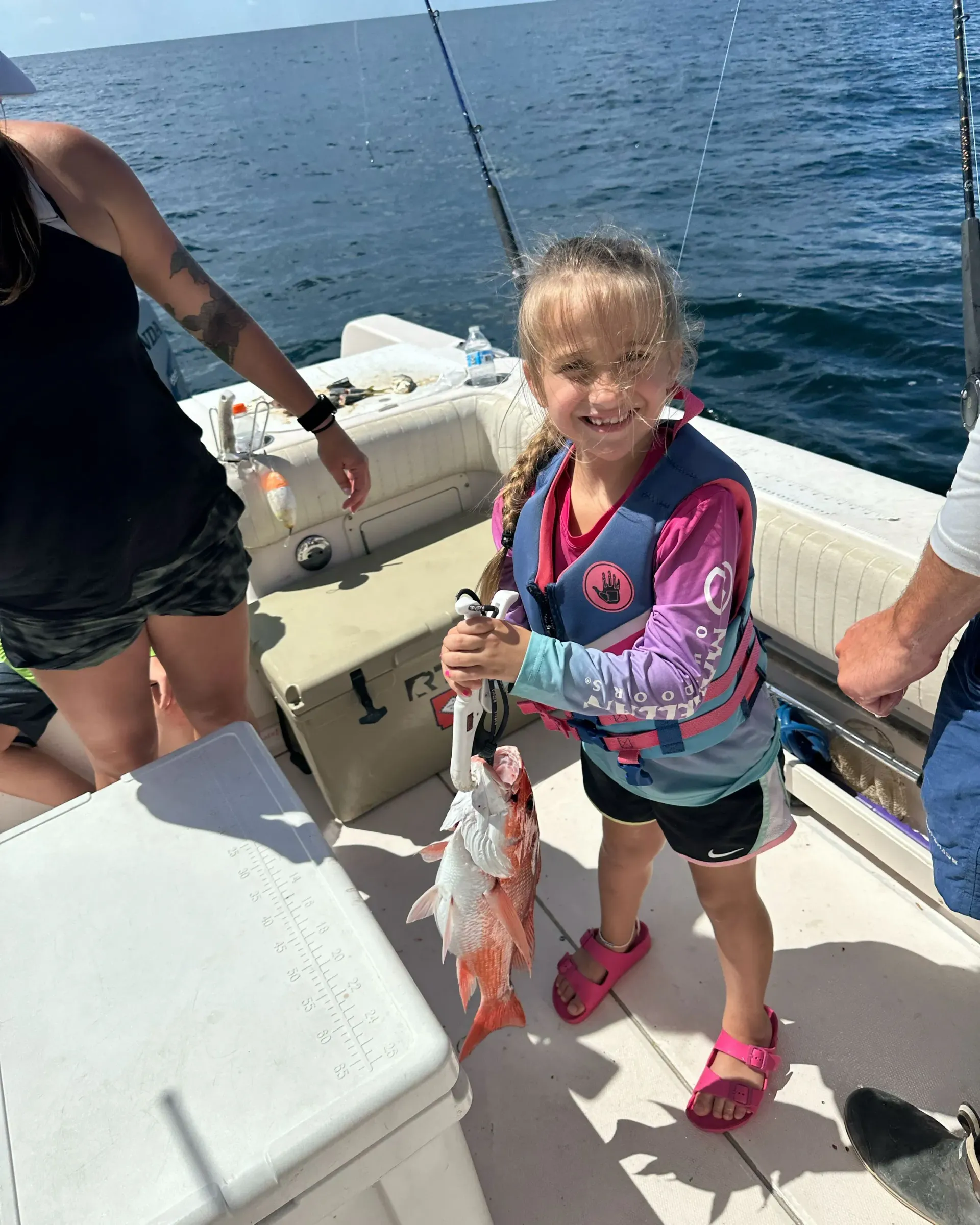 A little girl is holding a fish on a boat.