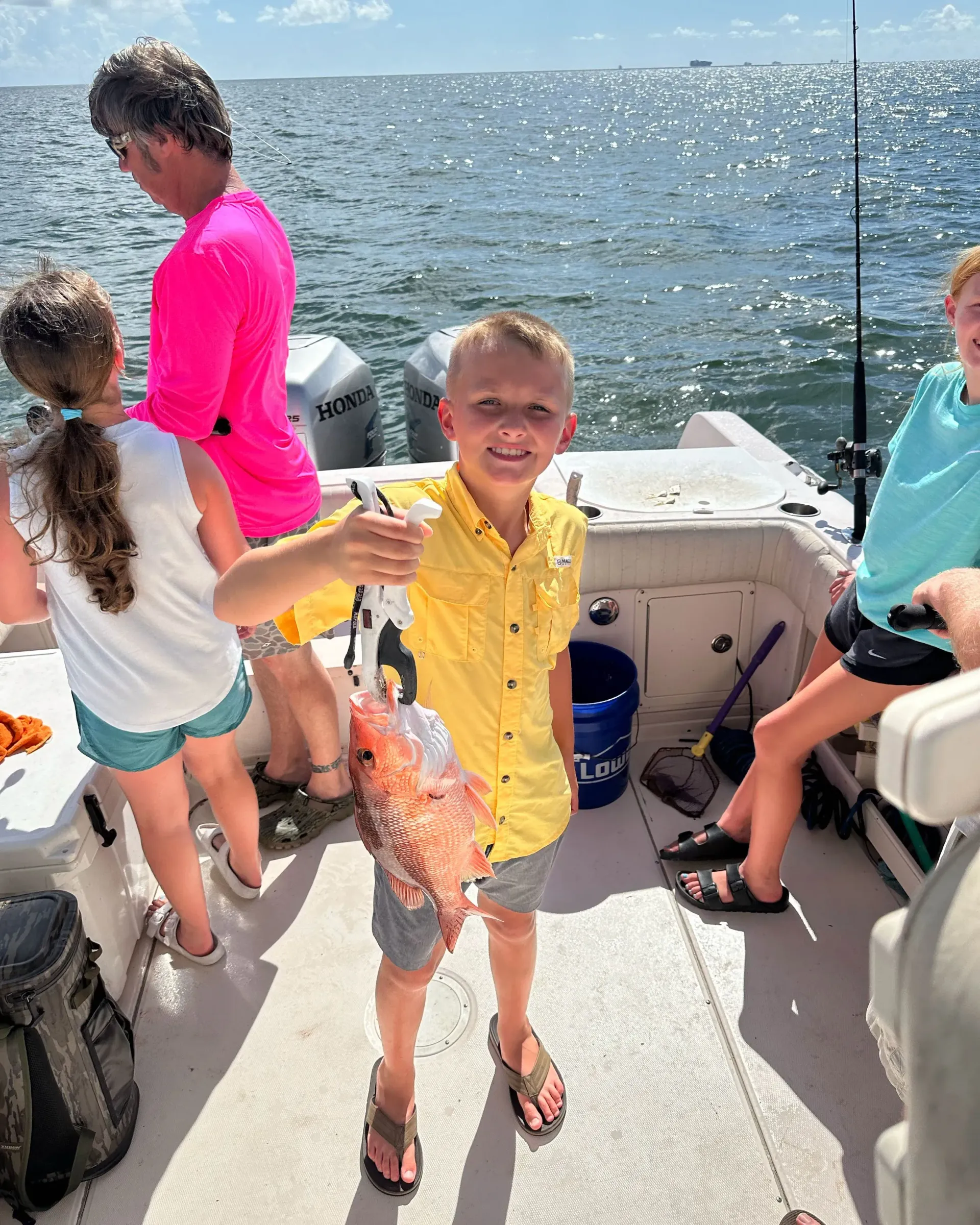 A young boy is holding a fish on a boat.