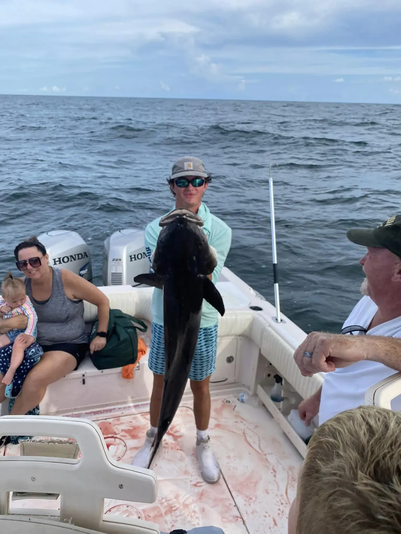 A man is holding a large fish on a boat.
