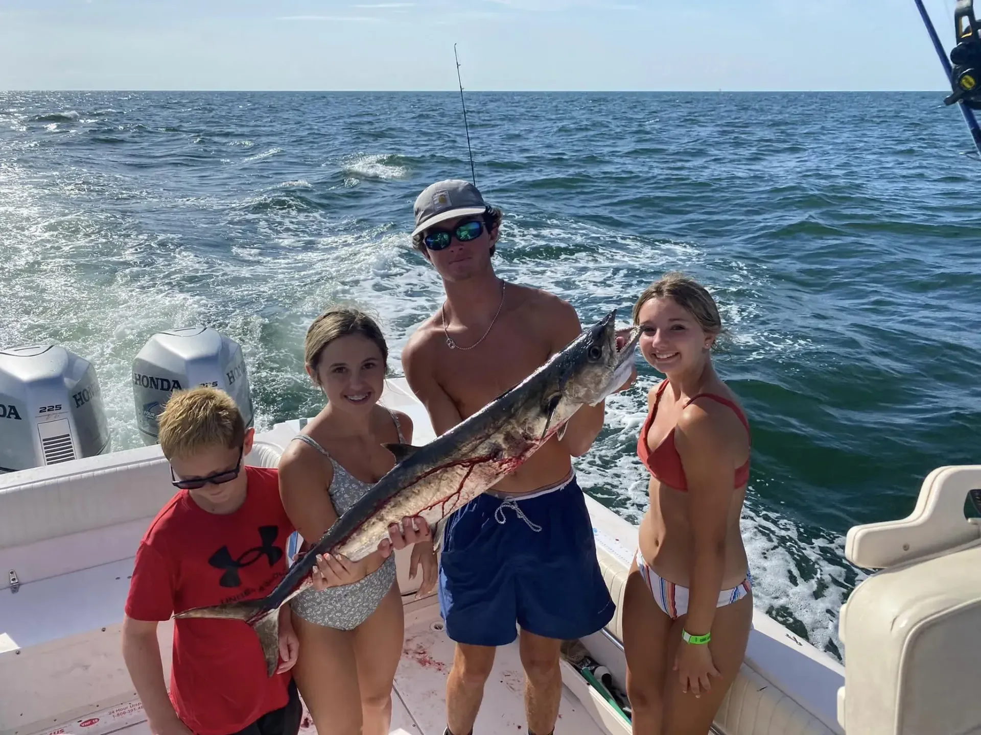 A group of people are standing on a boat holding a large fish.