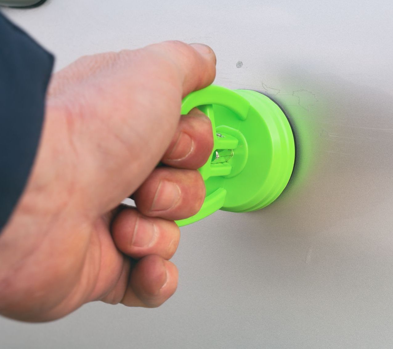 A person is holding a green object on a car door.