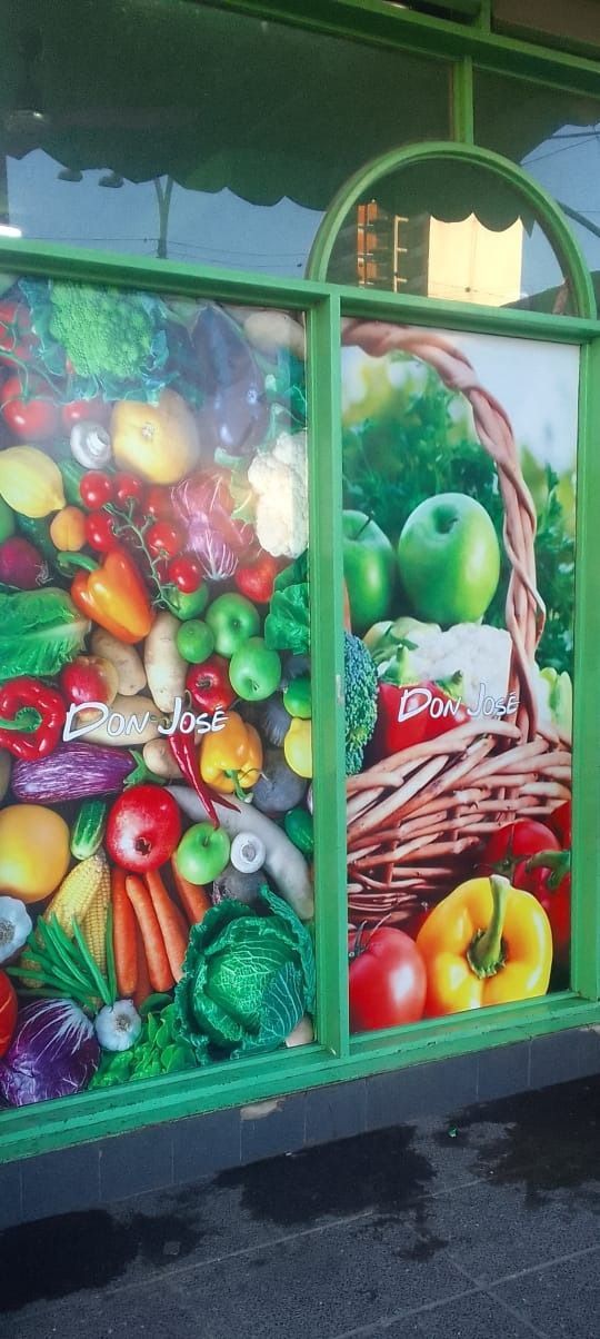 Escaparate con frutas y verduras de colores vibrantes, con una cesta de productos a la derecha.