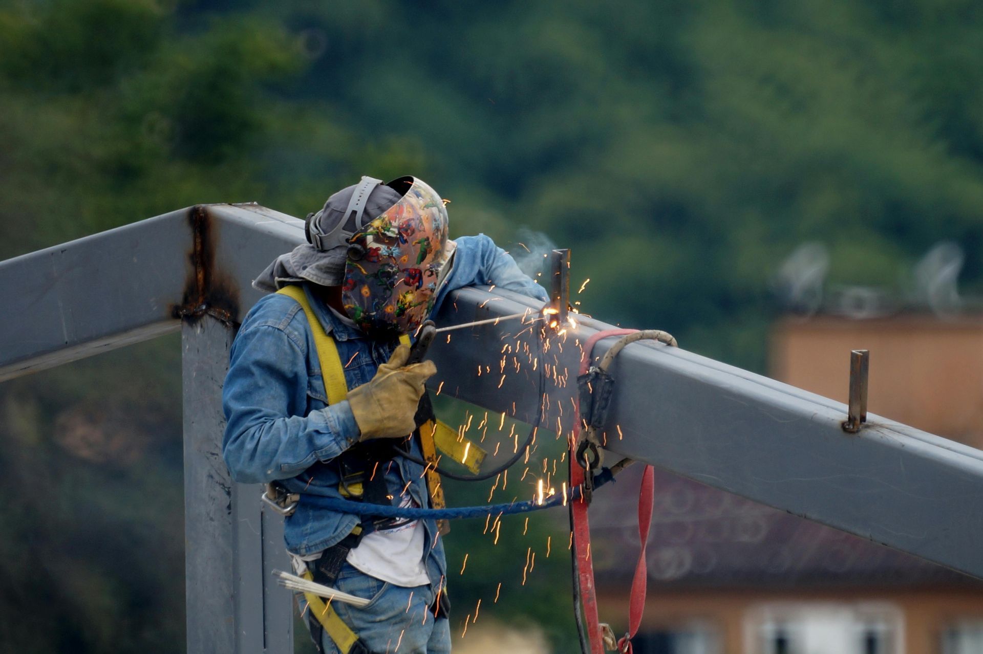 A man is welding a metal structure on top of a bridge.