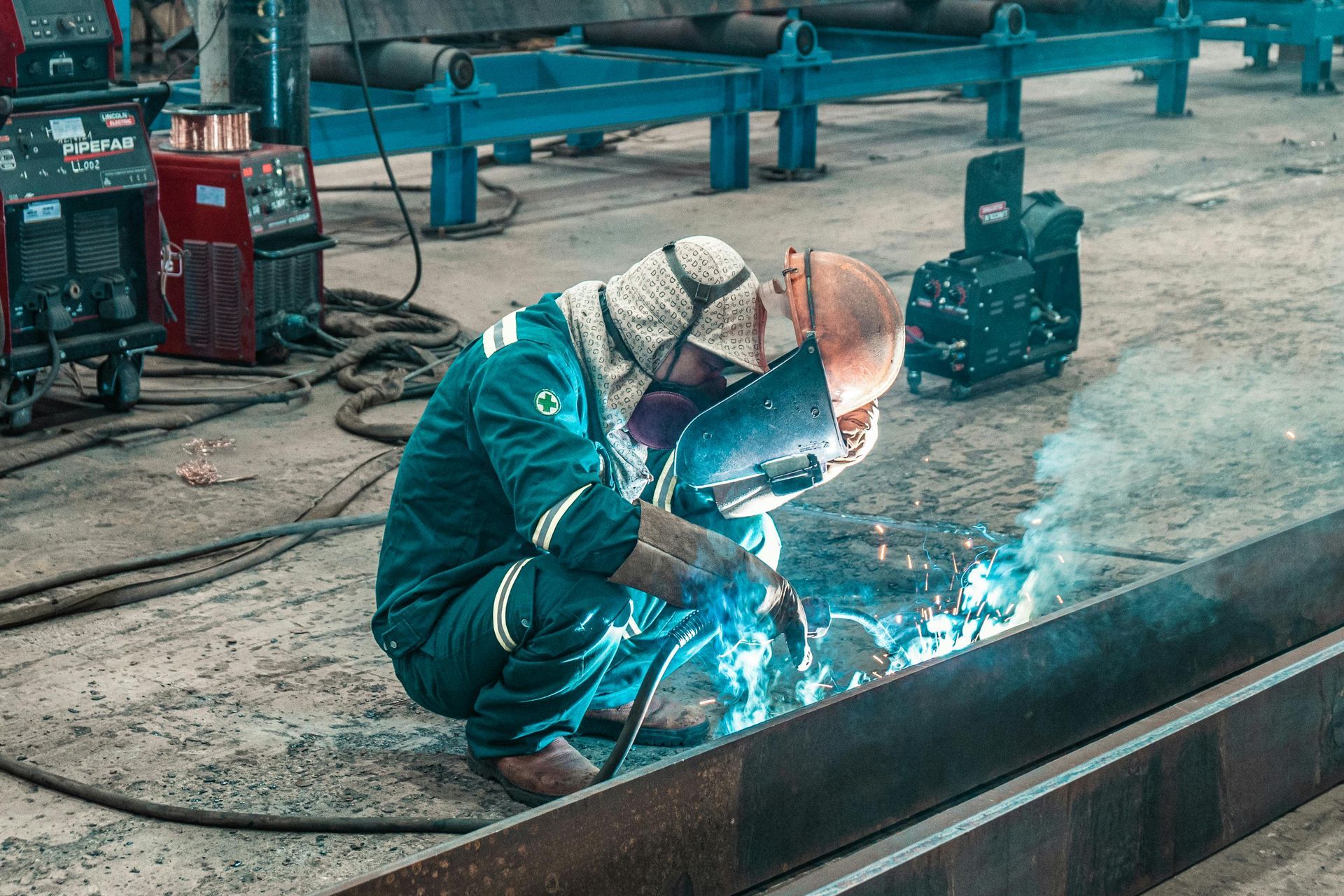 A man is welding a piece of metal in a factory.