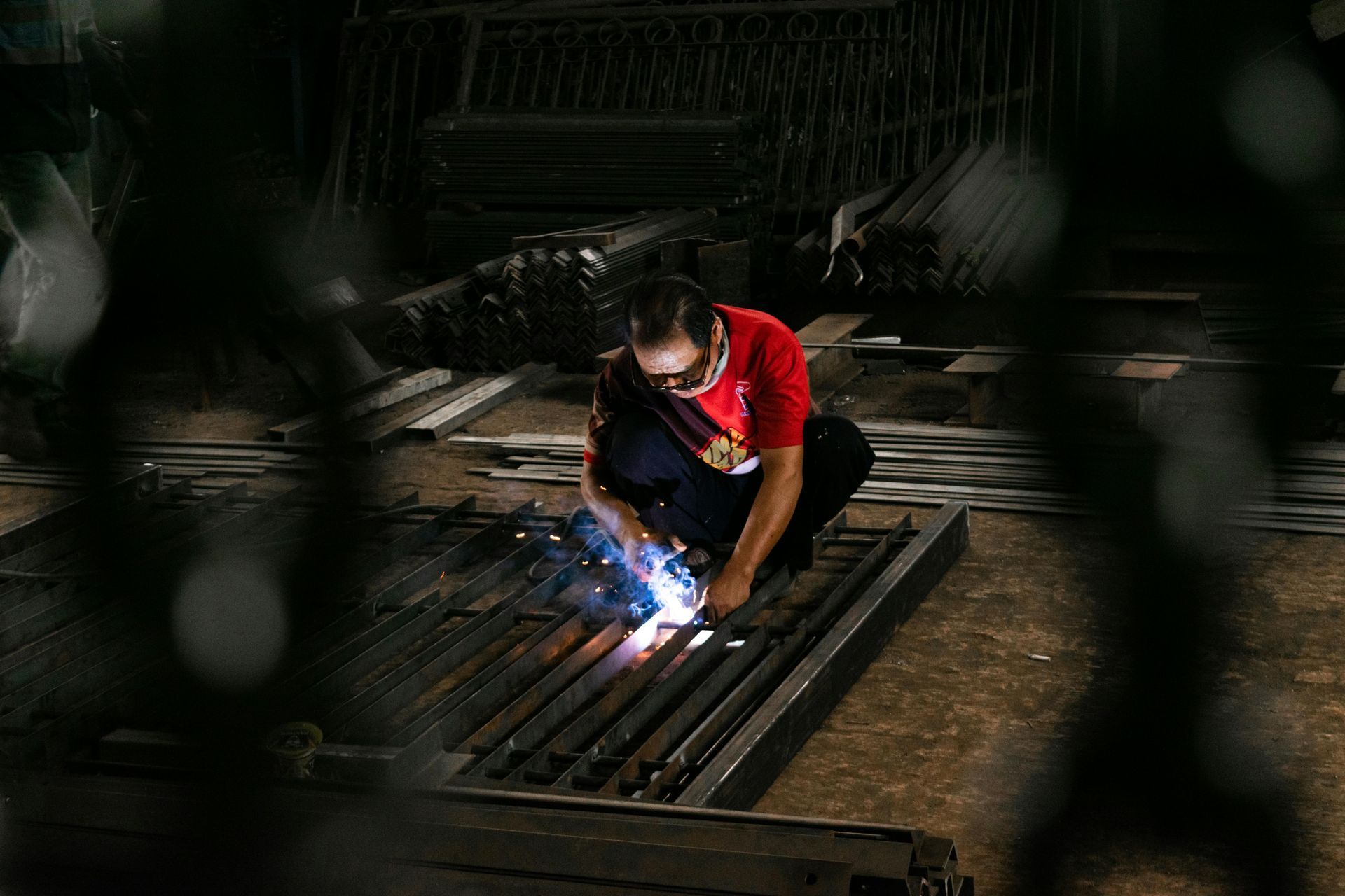 A man is welding a metal gate in a factory.
