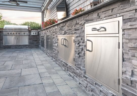 An outdoor kitchen with stainless steel cabinets and a grill.