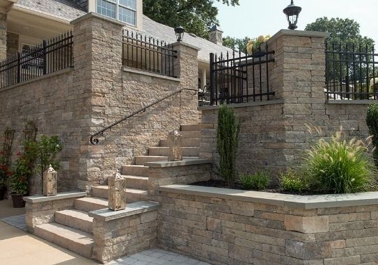 A stone wall with stairs leading up to the front of a house.