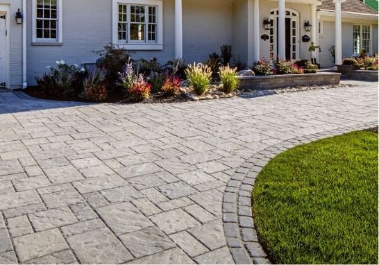 A driveway leading to a house with a brick walkway