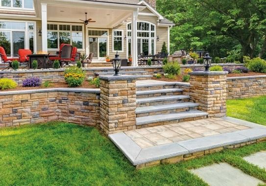 A house with a stone wall and stairs in front of it.