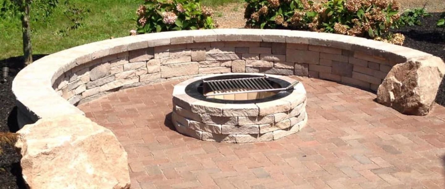 A fire pit is surrounded by bricks and rocks on a patio.