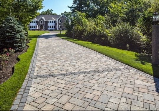 A brick driveway leading to a large house