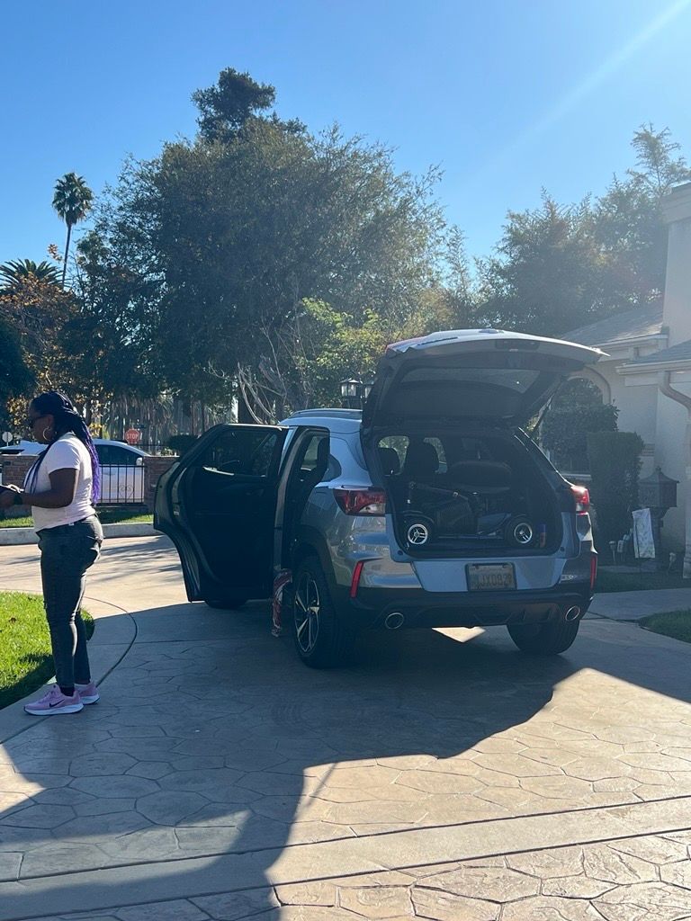 A woman is standing next to a car with the trunk open.