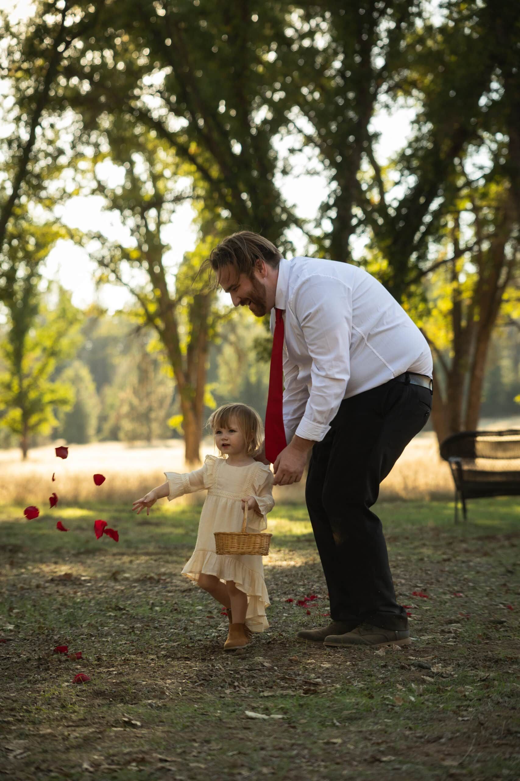 A man is holding the hand of a flower girl in a field.