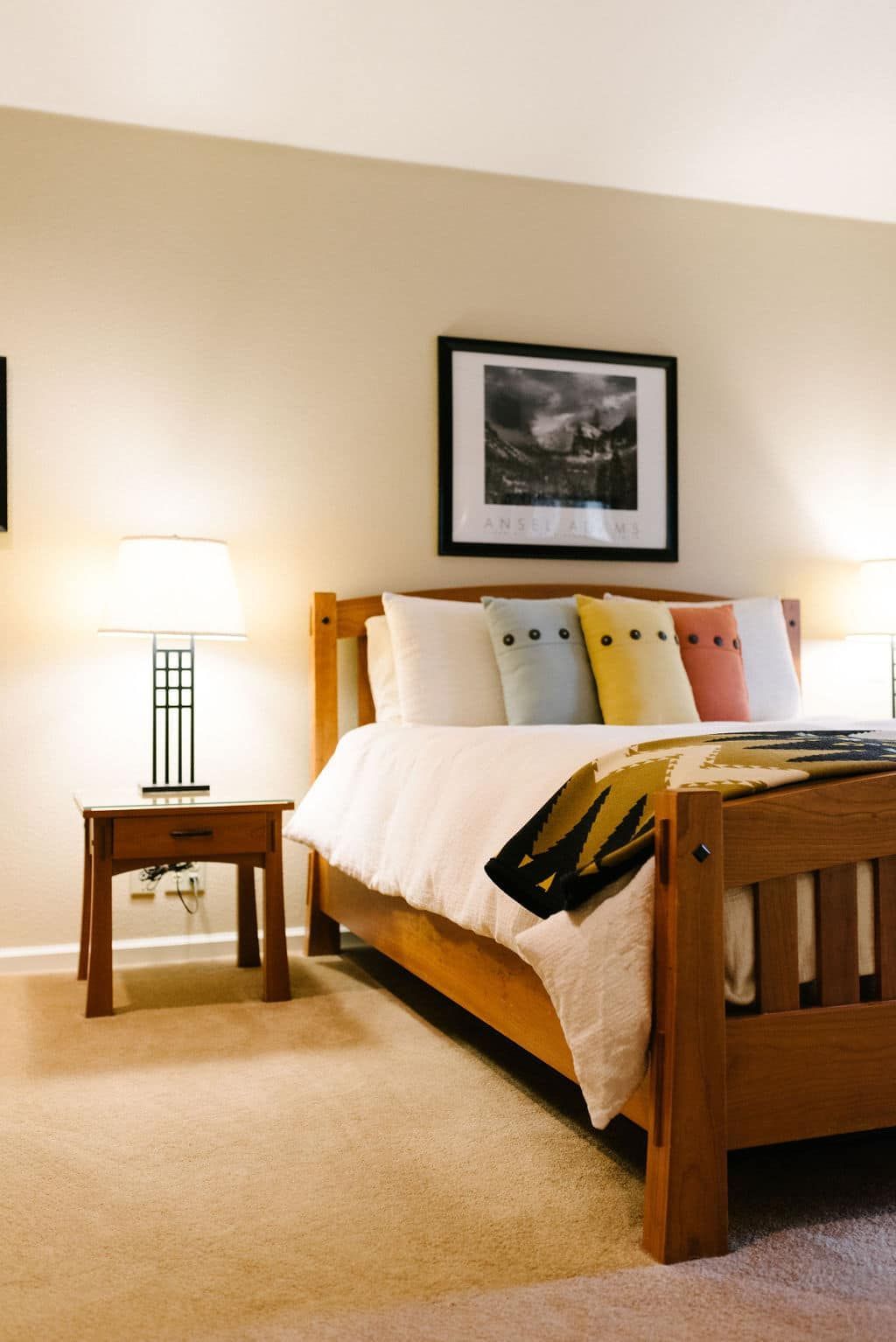 A bedroom with a bed a nightstand and a lamp