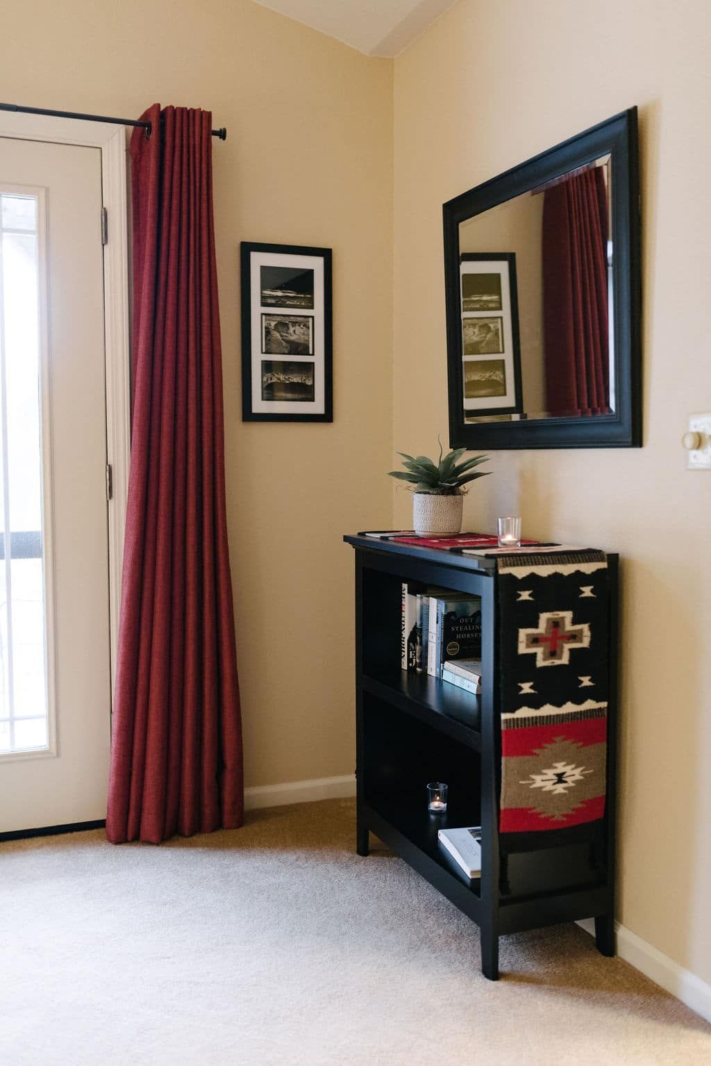 A corner of a room with a shelf and a mirror