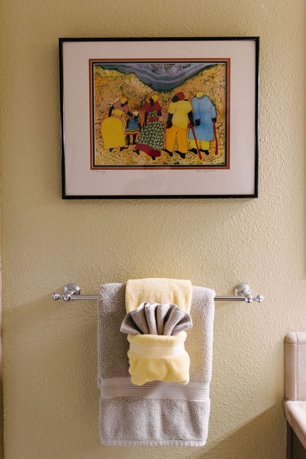 A bathroom with a picture on the wall above the towels