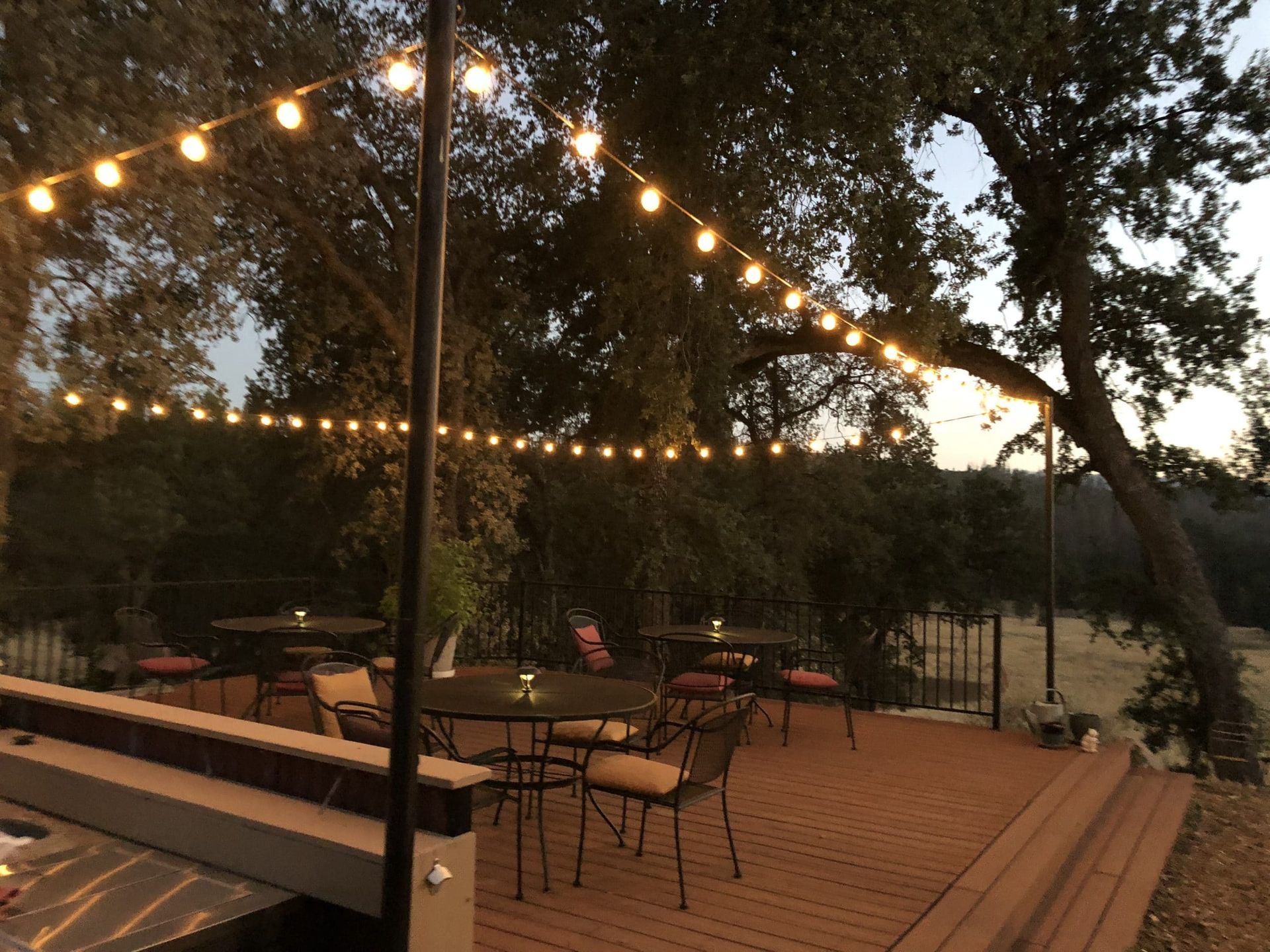 A deck with tables and chairs and a string of lights